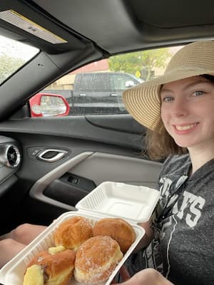 author posing with a tray of malasadas