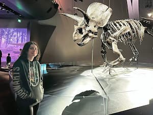 author standing beside dinosaur fossil