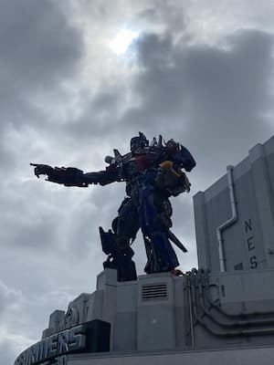 Optimus Prime standing on a building pointing out into the distance