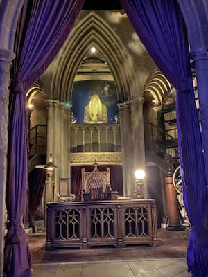 a hologram of Dumbledore from Harry Potter standing at the top of his office balcony