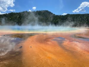 a large steaming hot spring around a mineral orange ground